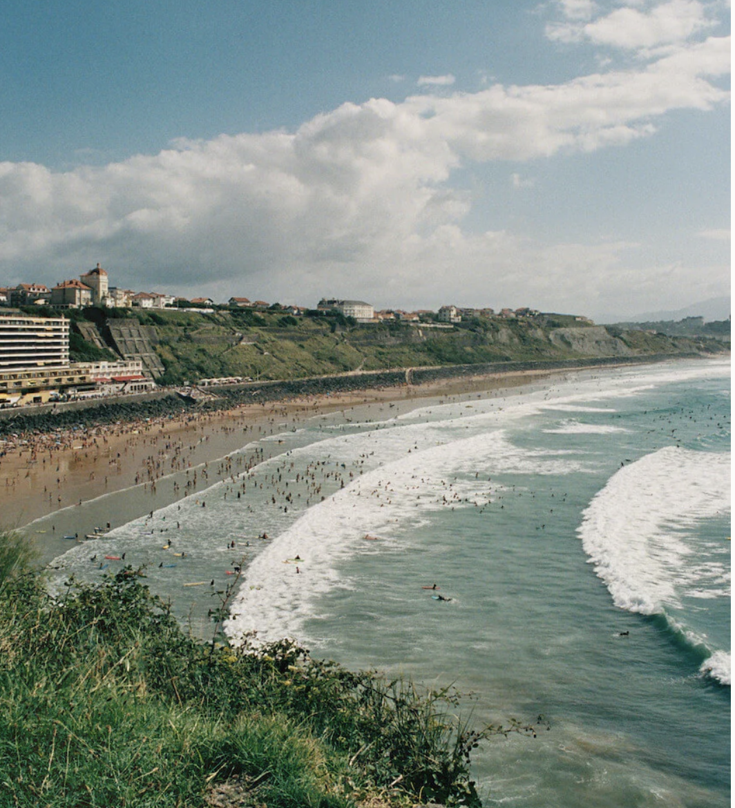 Surfers and bathers along the Biarritz coastline on a bright summer day